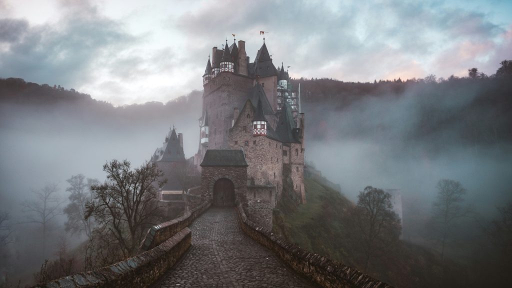 A stone path leading up to a castle surrounded by fog.
