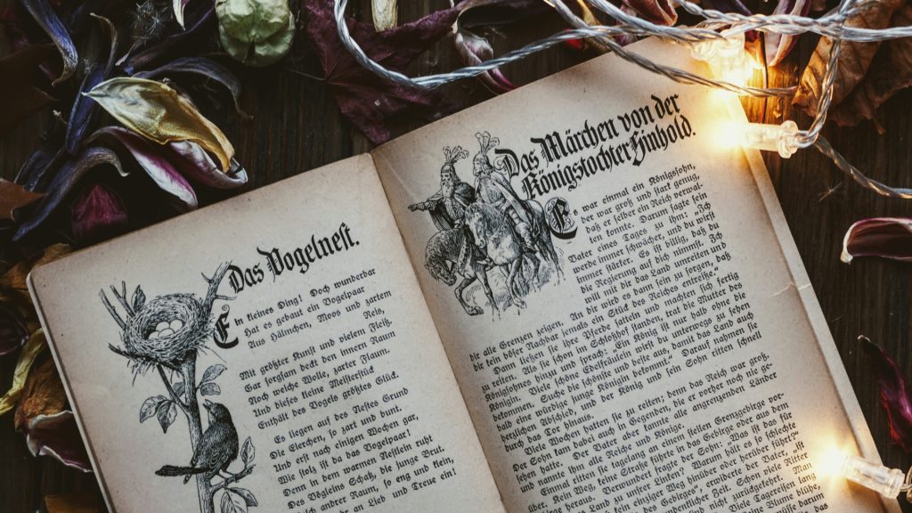 A close up of a book with fantasy illustrations and what appears to be elvish style writing.