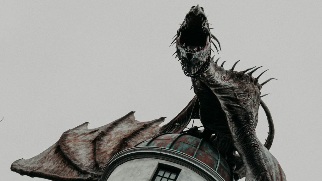 A dragon statue circled around the top of a building roof.